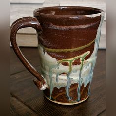 a brown and white coffee cup sitting on top of a wooden table