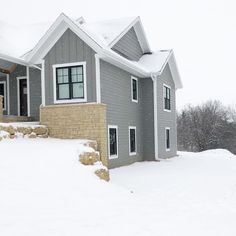 a house with snow on the ground and trees in the background