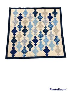 a blue and white quilt with squares on it's sides, in the shape of diamonds