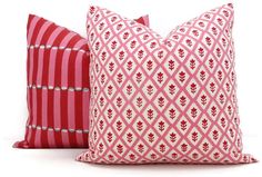 two red and white pillows sitting next to each other