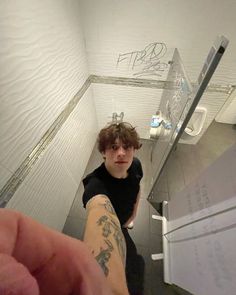 a young man is taking a selfie in the bathroom with graffiti on the walls