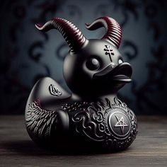 a black ceramic animal with horns and wings on it's head sitting on a table