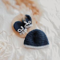 two crocheted hats and booties laying on a bed