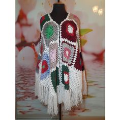 a crocheted vest with flowers and fringes on the front, sitting on a mannequin