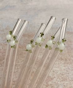 four glass straws with green beads on them