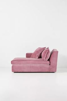 a pink velvet chaise lounger with two pillows on the back and one arm