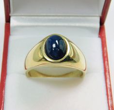 a gold ring with a blue stone in it's center sits inside a red box