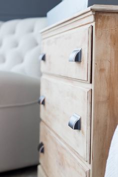 a white bed sitting next to a wooden dresser with two drawers on top of it