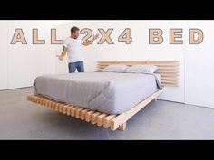 a man standing next to a bed made out of wood