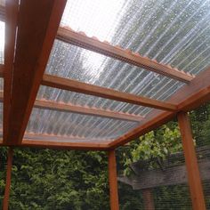 a wooden pergolated covered patio with trees in the background