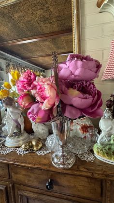 there are many flowers in the vases on the dresser top, and one is pink