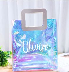 a plastic bag with the name ulvia on it sitting on a table next to a plant