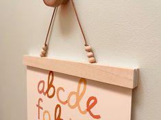 a wooden sign hanging from the side of a wall with beads on it's string