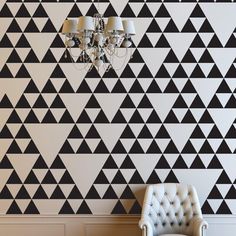 a chair and chandelier in front of a black and white geometric wallpaper