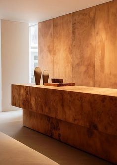 two vases sitting on top of a wooden counter in a room with white walls