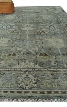 a large rug with an intricate design and fringes on the bottom is sitting next to a footstool