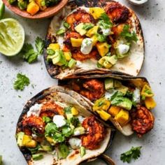 three fish tacos with avocado, mango salsa and cilantro on the side