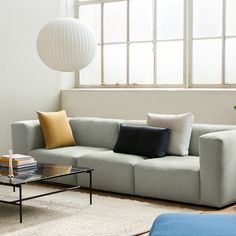 a living room with a couch, coffee table and lamp in front of a window