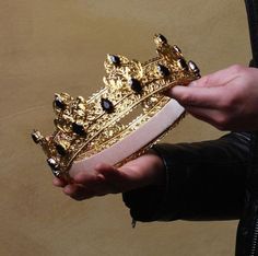 a person holding a gold crown in their hands