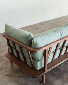 a wooden bench with green cushions on it