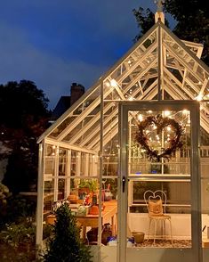 a white house with christmas lights on the roof and windows in front of it is lit up at night