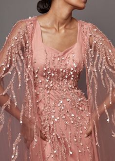 a woman wearing a pink dress with sequins on it and a veil over her head