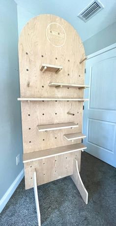 a wooden shelf sitting in the middle of a room with shelves on each side and pegs at the bottom