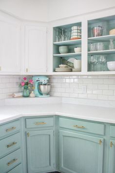 a kitchen with blue cabinets and white counter tops is pictured in this image, there are dishes on the shelves