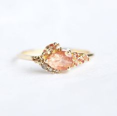 a gold ring with two different colored stones on the front and side, sitting on a white surface