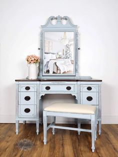 a blue vanity with a mirror and stool in front of it on a wooden floor