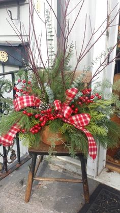 a potted plant with red berries and greenery on an old wooden chair in front of a store