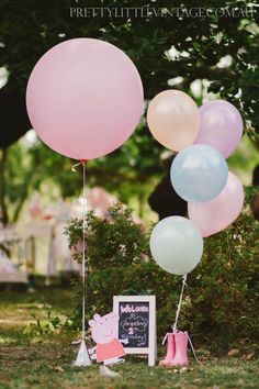 some balloons that are in the grass near a chalkboard and an old photo frame