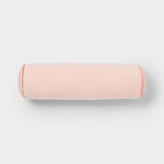 a pink rolled up pillow on a white background