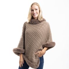 Elevate your cold-weather wardrobe with the FurTrimmed CozyCable Poncho, a luxurious blend of warmth, style, and sophistication. This cable knit poncho is crafted from soft 100% polyester, offering a cozy feel while draping beautifully over your shoulders. The warm brown hue adds richness and depth, while the fancy faux fur trim along the neckline and edges brings an extra touch of elegance. Designed with the flexibility of a poncho, this piece is perfect for layering over your favorite outfits. Cable Knit Outerwear In One Size, Winter Soft Knit Poncho One Size, Winter Cable Knit Outerwear One Size, Cozy Soft Knit Winter Poncho, Cozy Winter Poncho For Cold Weather, Winter Chunky Knit Poncho, Cozy Knitted Winter Cape, Winter Poncho With Faux Fur Trim, Brown Knit Poncho For Winter