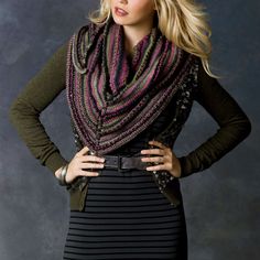 a woman wearing a black dress and a striped scarf is standing with her hands on her hips