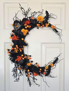 a wreath made out of branches and pumpkins on the front door, decorated with black mesh