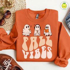 Capture the essence of fall with this charming sweatshirt featuring three adorable ghosts: one singing, one reading, and one enjoying music, all under the cozy message 'Fall vibes.' Perfect for autumn lovers and those who appreciate a blend of spooky and serene, this pullover is ideal for chilly fall days, Halloween gatherings, or simply relaxing with your favorite fall activities. Made from soft, high-quality fabric, it's designed to keep you warm and stylish throughout the season. Celebrate the joys of autumn with this delightful and cozy sweatshirt! Cute Sweater For Fall Streetwear, Cute Fall Sweatshirt With Funny Print, Cute Fall Sweatshirt For Streetwear, Cute Fall Streetwear Sweatshirt, Cute Sweatshirt For Fall Streetwear, Funny Print Long Sleeve Sweatshirt For Fall, Cute Streetwear Sweatshirt For Fall, Long Sleeve Sweatshirt With Funny Print For Fall, Fall Sweatshirt With Funny Print And Relaxed Fit