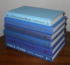 a stack of blue books sitting on top of a wooden table next to a white wall