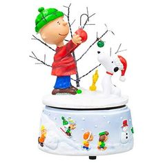 a charlie brown christmas ornament on top of a white base with trees and snow