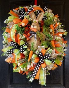 a wreath that is decorated with carrots, grass and a bunny on the front door