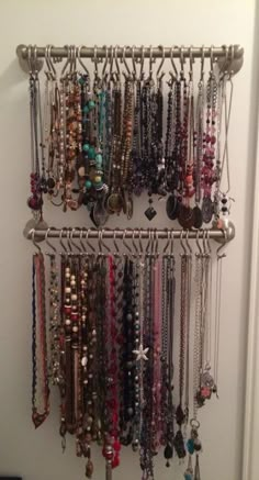 a bunch of necklaces are hanging on a metal rack next to a white door