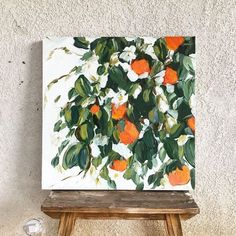 an orange tree is shown on the easel in front of a white wall and wooden stool