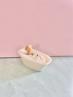 a small white bowl filled with food next to a pink wall