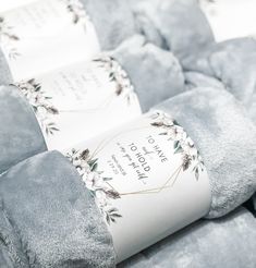 two gray blankets with white and pink flowers on them, one is rolled up to show the label