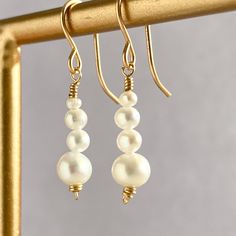 "This beautifully simple pair of dangle earrings are lovingly handmade with eight tiny Freshwater Pearls and a choice of a 14k Solid Gold, 14k Gold Filled, 14k Rose Gold Filled or Sterling Silver finish. M A T E R I A L S: * Freshwater Pearl  * 14k solid Gold, 14k Gold Filled, 14k Rose Gold Filled or Sterling Silver S I Z E: *  Gemstone - Approximately 3-6mm All of our jewellery is carefully handmade using good quality materials and handpicked gemstones, with the aim to produce quality pieces that you can love & wear for years to come.  P E A R L: * June Birthstone * Talisman for Gemini, Cancer * Third Eye Chakra Pearl signifies faith, charity and innocence. It enhances personal integrity and helps to provide a focus to ones attention. Pearl symbolises purity and is known as a \"stone of s Classic Round Linear Earrings For Gifts, Classic Round Linear Earrings Gift, Elegant Adjustable Earrings For Anniversary, Handmade 14k Gold Filled Pearl White Jewelry, Graceful Drop Earrings With Matching Set, Delicate Linear Earrings With Ear Wire For Anniversary, Handmade 14k Gold Filled Elegant Earrings, Elegant Wire-wrapped Yellow Gold Pearl Earrings, Elegant Yellow Gold Wire Wrapped Pearl Earrings