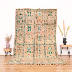 an old rug is displayed in front of a table with two vases on it