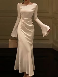 Experience the jazz-age revival with this elegantly designed white gown, complete with bell sleeves that add a vintage touch to a modern silhouette. The sleek bodice highlights the natural waistline, while the gently flaring skirt creates a flowing movement as you walk. Made from premium fabric that hugs the body while allowing for a full range of motion, this dress combines the best of both comfort and style. It’s a contemporary take on classic glamour, perfect for evenings where making a graceful impression is key. Size Bust (cm) Waist (cm) Hips (cm) Dress Length (cm) Sleeve Length (cm) S 90 74 - 136 62 M 94 78 - 137 63 L 98 82 - 138 64 XL 102 86 - 139 65 XXL 106 90 - 140 66 XXXL 110 94 - 141 67 White Sleeved Dress, Modern Maxi Dress, Satin White Dress With Sleeves, Full Sleeve Dress Designs, White Dresses With Sleeves, Full One Piece Dress, Dresses With Flared Sleeves, White Dress Classy Elegant Long, Marriage Dresses For Women