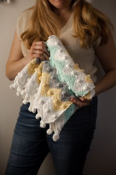 a woman holding a crocheted blanket in her hands