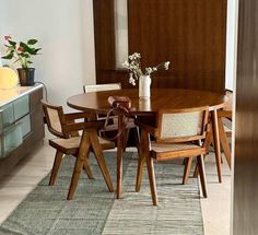 a dining room table with four chairs and a vase filled with flowers on top of it