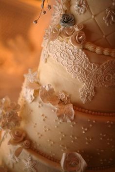 a three tiered wedding cake with lace and flowers